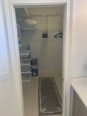 A narrow hallway with storage shelves, a vacuum cleaner, and a rug. - Island Time Starts Here! 3BR + Den Pool Retreat (Marco Island)