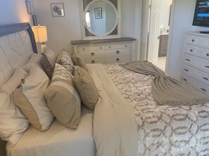 A bedroom with a bed, a dresser, a mirror, and a television. - Island Time Starts Here! 3BR + Den Pool Retreat (Marco Island)