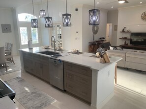 A modern kitchen with a central island, stainless steel appliances, and pendant lighting. - Island Time Starts Here! 3BR + Den Pool Retreat (Marco Island)