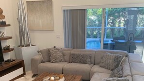 A modern living room with a sectional sofa, a coffee table, and a small side table. - Island Time Starts Here! 3BR + Den Pool Retreat (Marco Island)
