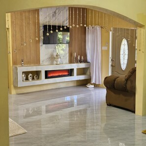 A modern living room with a fireplace, a sofa, and a TV mounted on the wall. - 2-bedroom house in wonderful Golden Grove with air conditioning (Golden Grove)