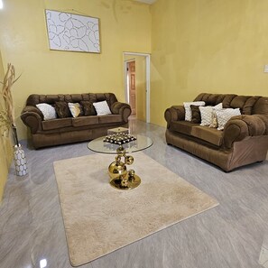 Ein Wohnzimmer mit zwei braunen Sofas, einem Glastisch und einem beigen Teppich.