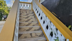 A staircase with a patterned tile floor, white balustrade, and yellow handrail. - 2-bedroom house in wonderful Golden Grove with air conditioning (Golden Grove)