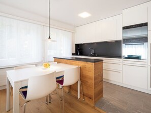 Eine moderne Küche mit weißen Schränken, einer Holzinsel und einer schwarzen Arbeitsplatte.