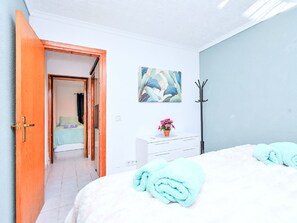 A bedroom with a bed, a dresser, a coat rack, and a door leading to another room. - Oasis 10 by Interhome (El Carmoli)