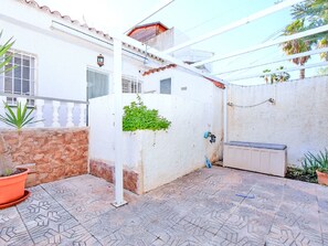 A patio area with a tiled floor, a white wall with a window, and a potted plant. - Oasis 10 by Interhome (El Carmoli)