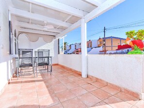 A covered outdoor area with tiled flooring, metal chairs, and a white wall. - Oasis 10 by Interhome (El Carmoli)