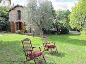 A stone building with a wooden door and windows, surrounded by a well-maintained lawn and trees. - Belvedere by Interhome (Gaiole in Chianti)