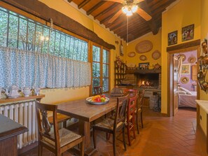 A rustic kitchen with a fireplace, wooden furniture, and a dining area with a fruit bowl. - Belvedere by Interhome (Gaiole in Chianti)