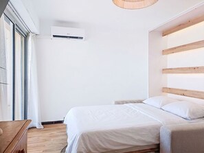 Una camera da letto con un letto, una testiera in legno, un comodino e una finestra con tende.