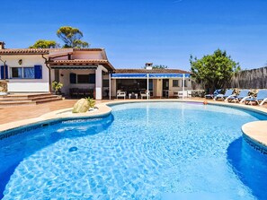 Piscina con solárium, mobiliario exterior y zona cubierta.