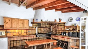 Uma cozinha rústica com armários de madeira, painel de azulejos e fogão embutido.