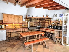Una cocina rústica con gabinetes de madera, salpicadero de azulejos y estufa empotrada.