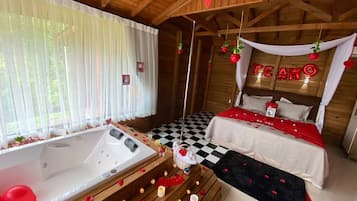 Una habitació acollidora amb un terra de pissos de graella, un llit amb roba de llit vermella i blanca, una banyera i un llit amb cortina on es llegeix 'LOVE'.