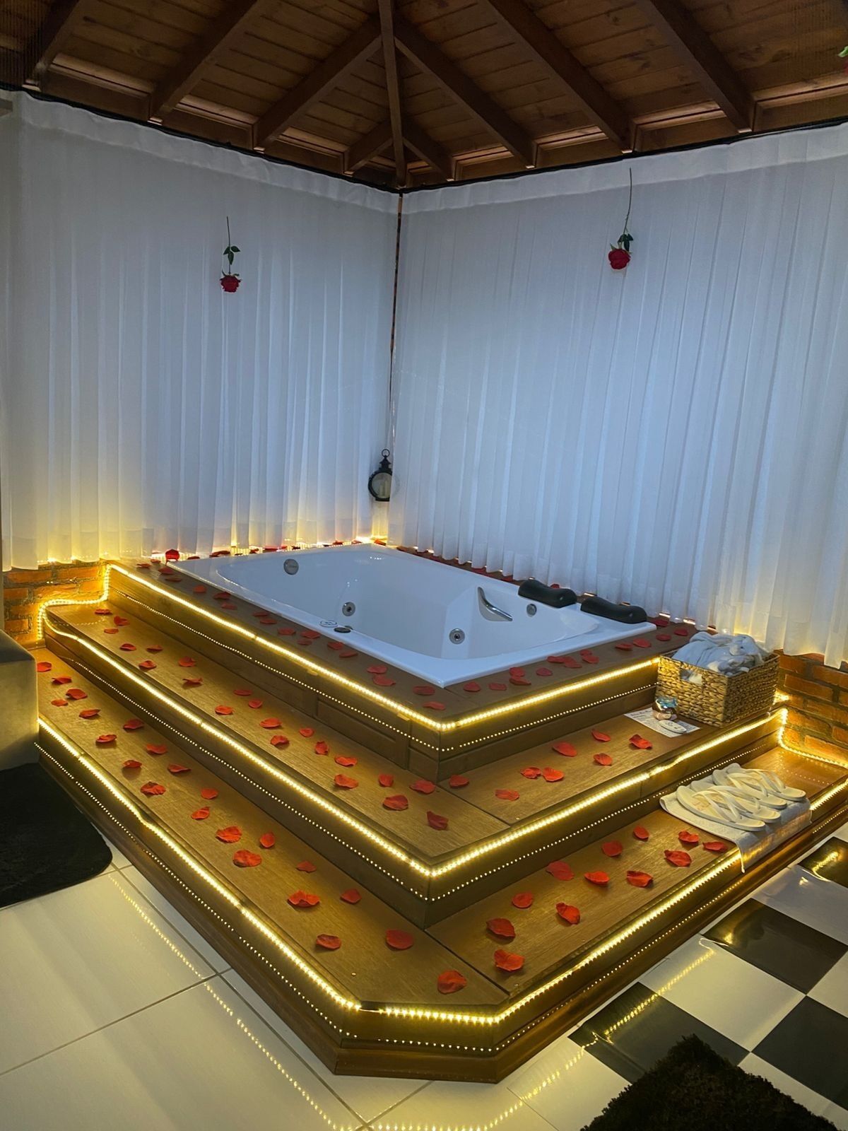 Un área de spa con un jacuzzi grande, escalones de madera y pétalos de rosa.