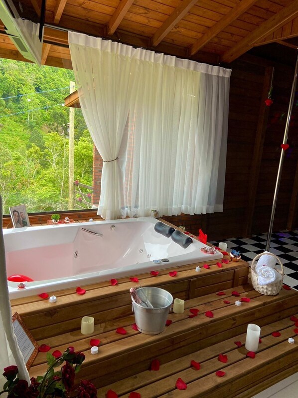 Una cabaña de madera con una bañera grande, escalones de madera y un suelo a cuadros.