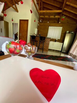 A dining table with a red heart-shaped card and two bowls of fruit.