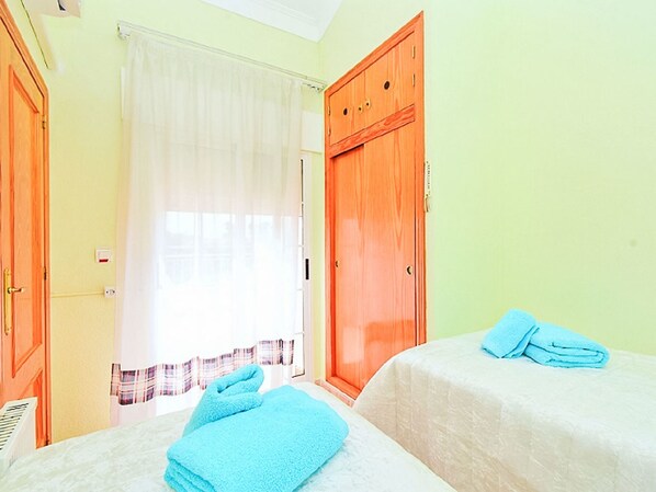 Ein Zimmer mit zwei Betten, einem Vorhangfenster und einem Holzschrank.