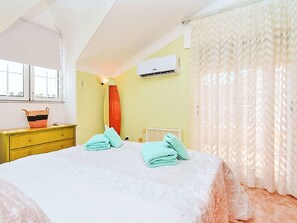A bedroom with a bed, a dresser, an air conditioner, and a window. - Olivos 3 by Interhome (Los Urrutias)