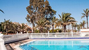 A swimming pool with a white fence and palm trees in the background. - Olivos 3 by Interhome (Los Urrutias)