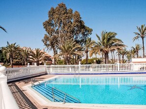 A swimming pool with a white fence and palm trees in the background. - Olivos 3 by Interhome (Los Urrutias)