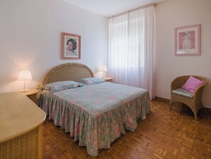 A bedroom with a bed, a chair, a table, and two lamps. - Appartamento La Terrazza di Anna by Interhome (Viareggio)