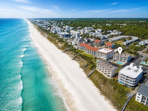 An aerial view of a coastal residential area with beachfront properties, a clear sky, and a calm sea. - Seagrove Beachside Retreat: Ocean and Pool Views: Private Beach: Sleeps 11 (Santa Rosa Beach)