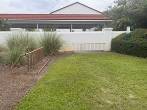 A well-maintained lawn with a metal fence and a covered area in the background. - Seagrove Beachside Retreat: Ocean and Pool Views: Private Beach: Sleeps 11 (Santa Rosa Beach)