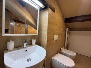A bathroom with a white sink, a mirror, a toilet, and a shower area. - Il Pittore by Interhome (Pisa)