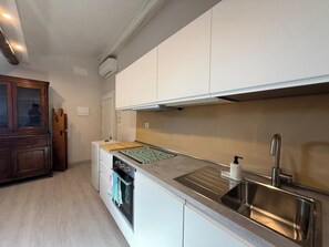 A modern kitchen with white cabinetry, a stainless steel sink, and a built-in oven. - Il Pittore by Interhome (Pisa)