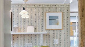 Uma cozinha com área de assento com banqueta de madeira, uma luminária pendente e um quadro na parede.