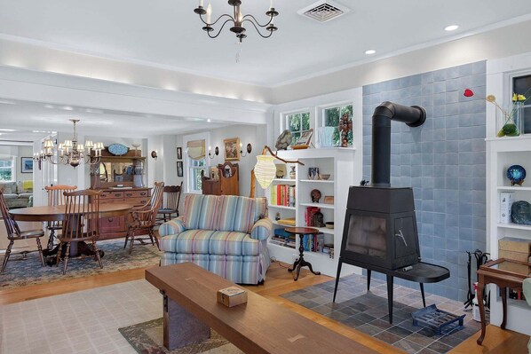 A cozy living room with a fireplace, a dining area, and a bookshelf.