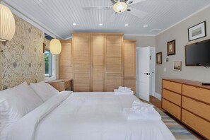 Un dormitorio con cama, armario, mesita de noche, lámpara y televisor.
