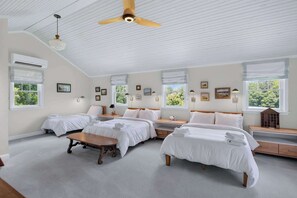 A bedroom with four beds, a ceiling fan, and large windows.