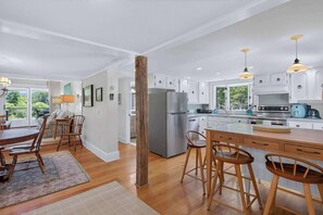 A modern kitchen with white cabinets, stainless steel appliances, and wooden bar stools.