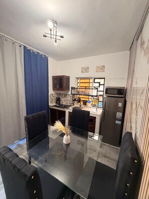 A modern kitchen with a dining area, featuring a glass table, black chairs, and a microwave. - (Paz) A place to stay and enjoy with the family. (Sosúa)