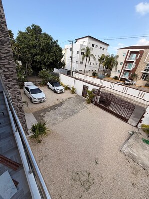 A residential area with a gated driveway, parked cars, and a building with multiple floors. - (Paz) A place to stay and enjoy with the family. (Sosúa)