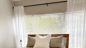 A bedroom with a wooden bed, white bedding, and sheer curtains. - Spacious Coastal-Style Home in Ravenna — Steps to UW, U-Village Mall, and more! (Seattle)