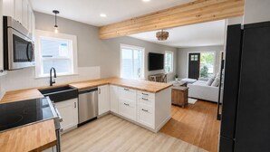 A modern kitchen with a dishwasher, microwave, and wooden countertop. - Spacious Coastal-Style Home in Ravenna — Steps to UW, U-Village Mall, and more! (Seattle)