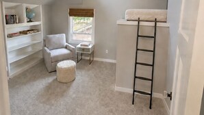 A compact room with a loft bed, a small seating area, and a bookshelf. - Spacious Coastal-Style Home in Ravenna — Steps to UW, U-Village Mall, and more! (Seattle)
