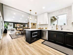 A modern kitchen with black cabinets, stainless steel appliances, and a central island.