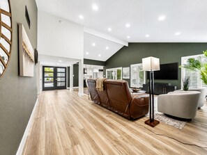 A modern living room with a brown leather sofa, a white armchair, and a floor lamp.