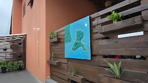 Una pared con un mapa, listones de madera, plantas en macetas y una reja de metal.