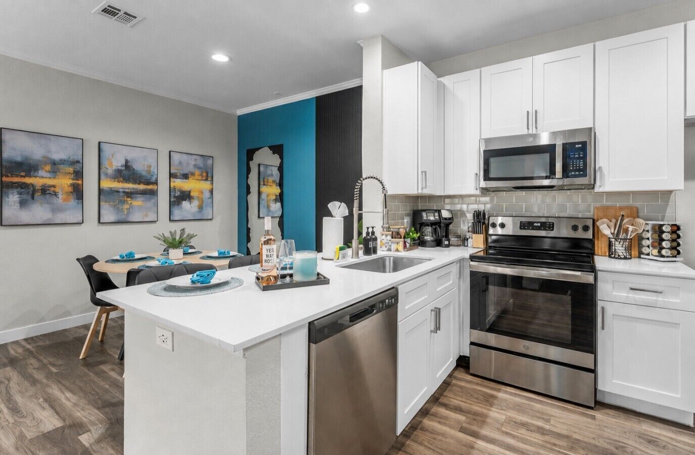 A modern kitchen with white cabinetry, stainless steel appliances, and a central island with a dishwasher.