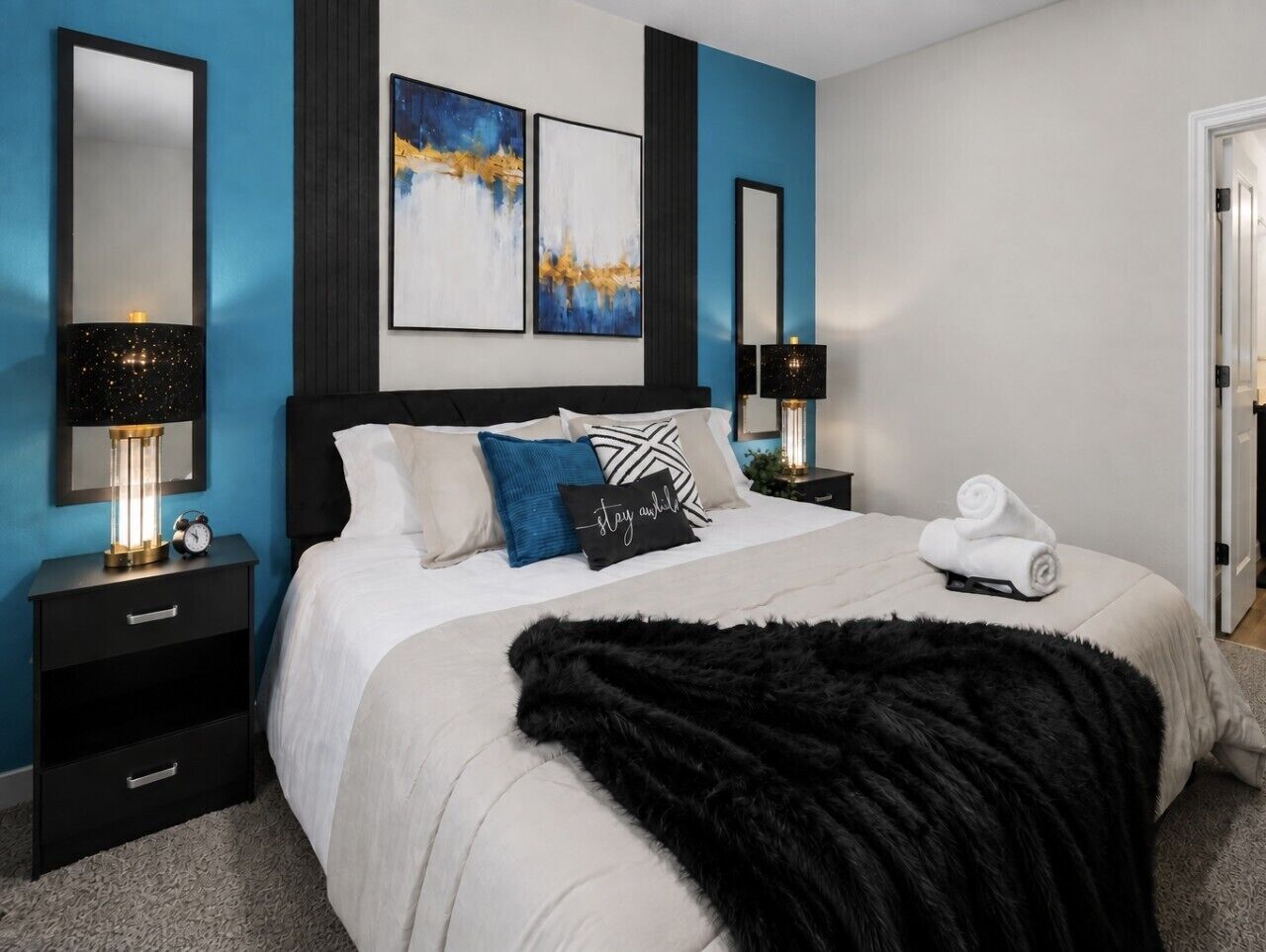 A bedroom with a bed, nightstands, a black fur throw, and artwork on the wall.