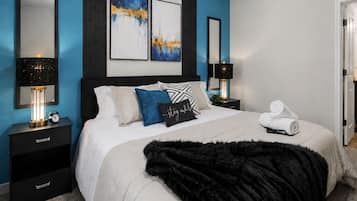 A bedroom with a bed, nightstands, a black fur throw, and artwork on the wall.