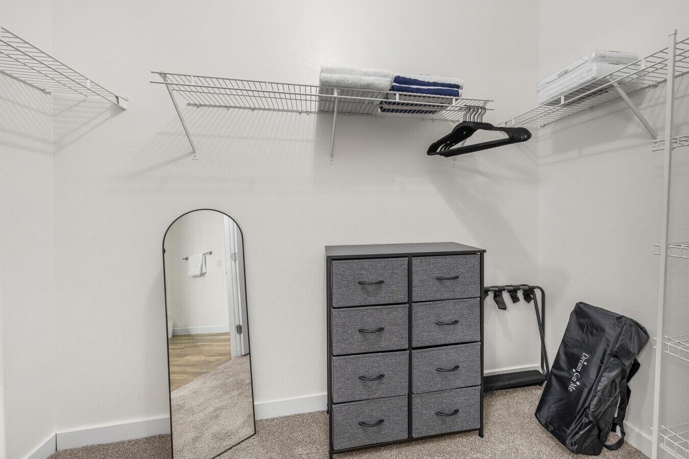 A compact room with a wardrobe, a mirror, a hanging rack, and a bag.