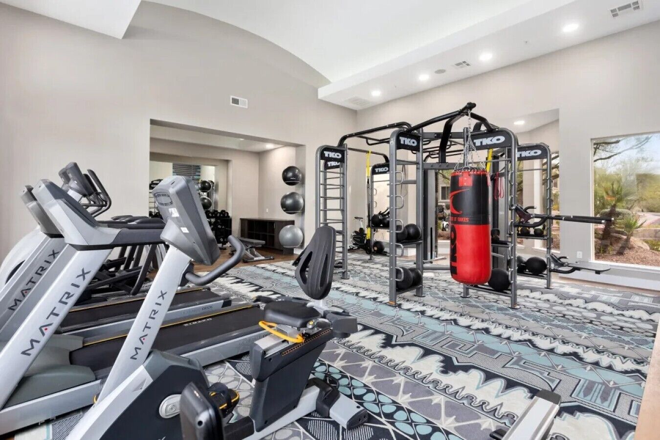 A gym with treadmills, a weightlifting station, and exercise balls.
