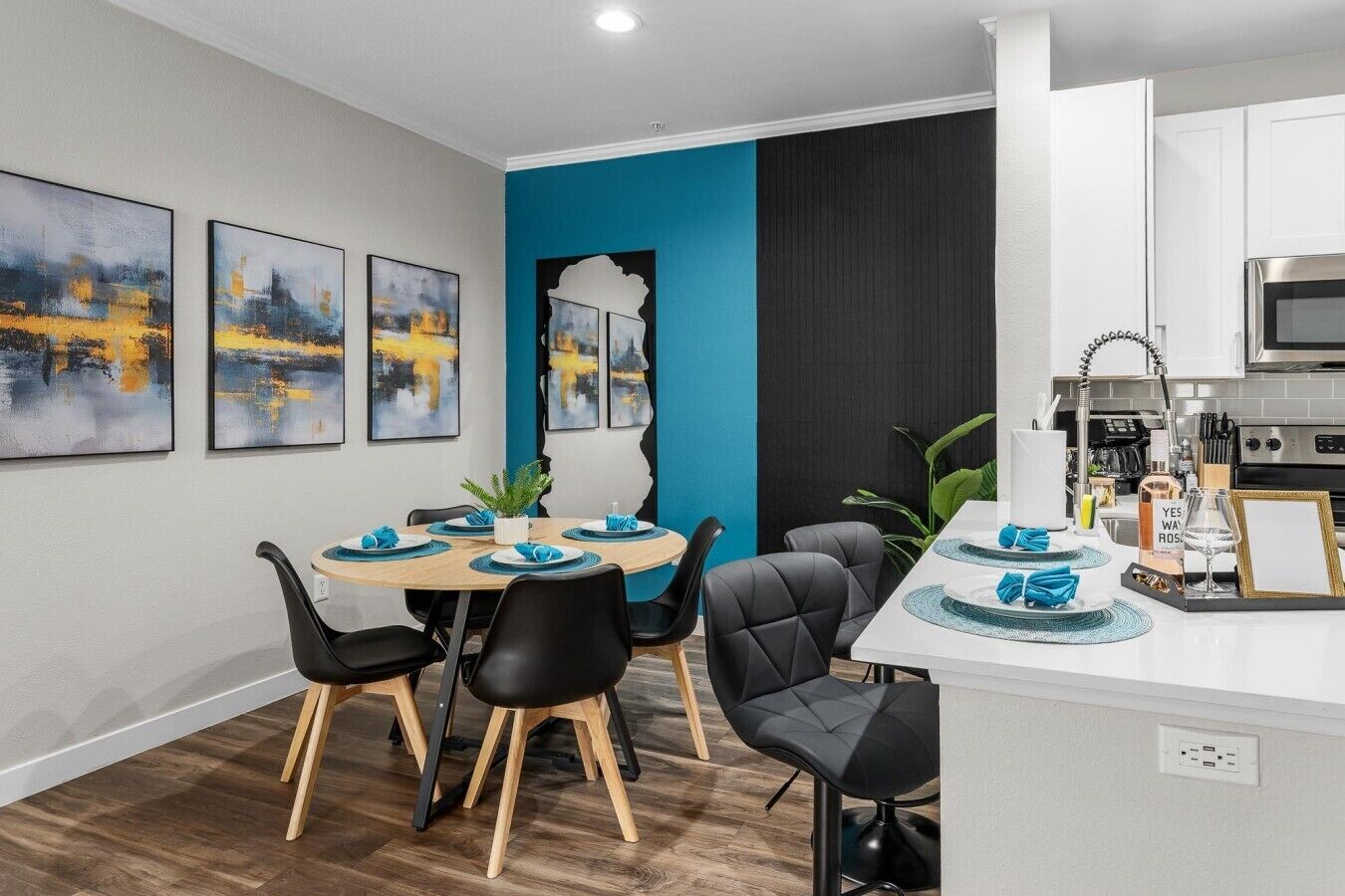 A modern dining area with a round table, black chairs, and blue napkins.