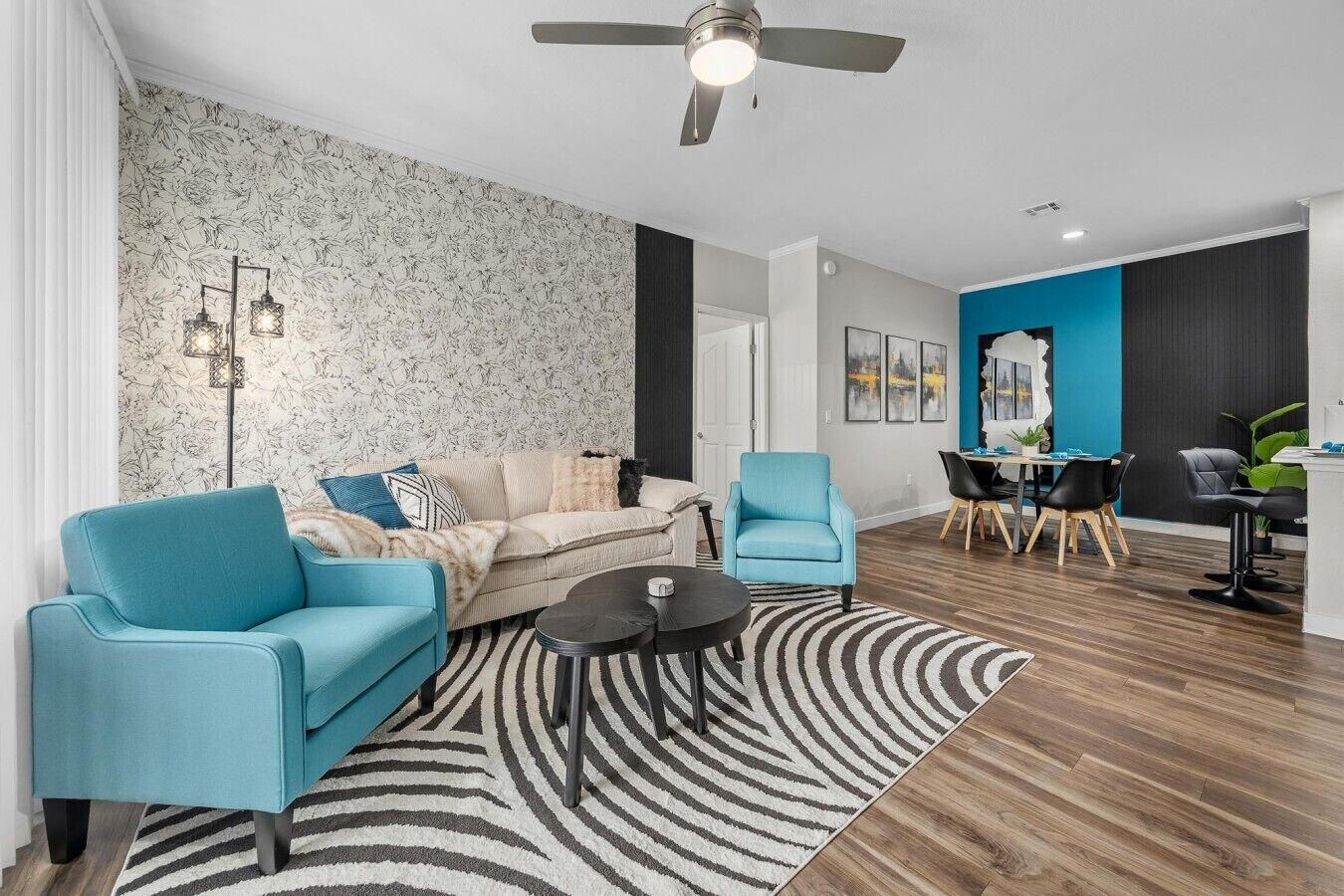 A modern living room with a sofa, armchairs, a coffee table, and a dining area with chairs and a table.